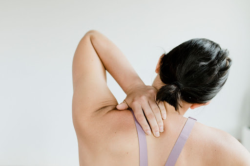 woman placing her hand on back of neck